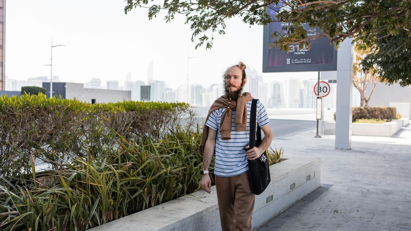 a man walking down a sidewalk with a scarf around his neck