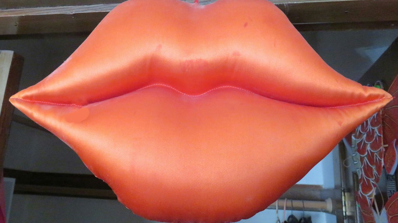 a large orange lip shaped balloon hanging from a ceiling