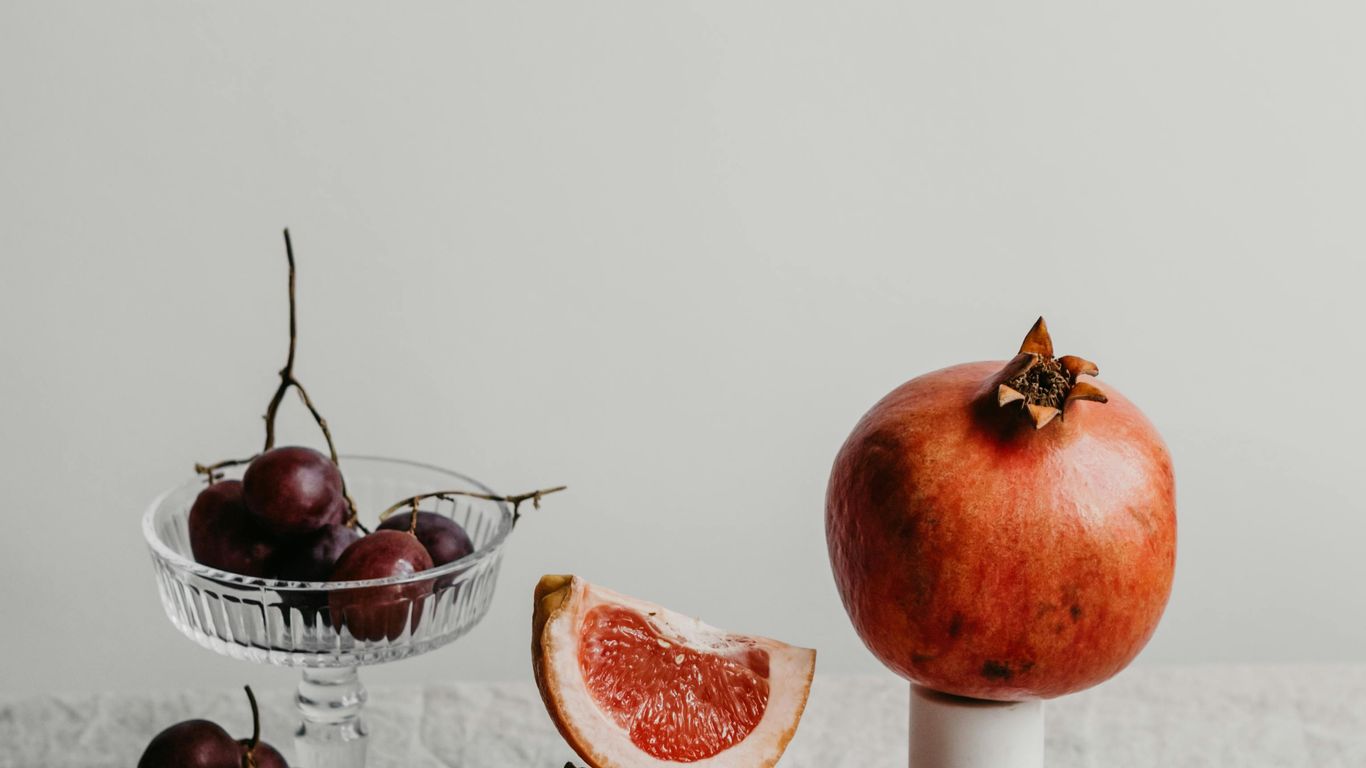 Assorted fruits including grapefruit, grapes, and pomegranate on table.