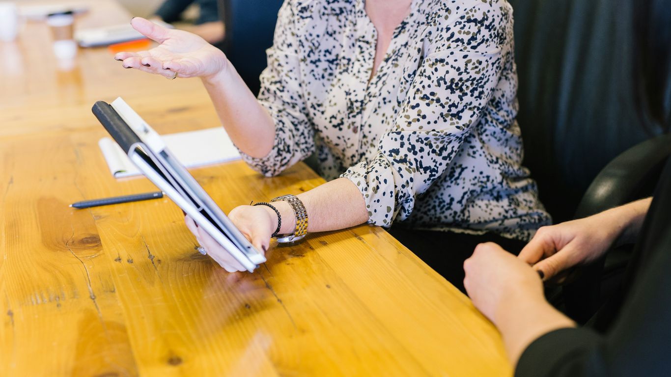woman holding tablet computer showing to seatmate