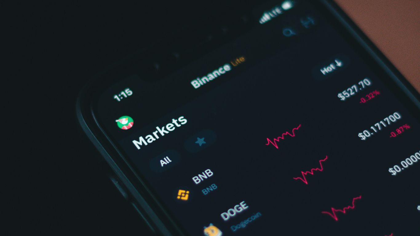 A close-up of a smartphone displaying cryptocurrency market graphs.