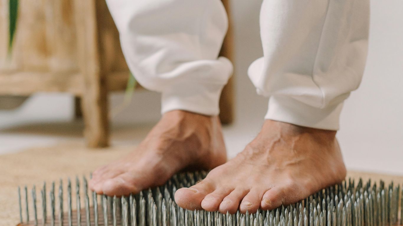 Person standing barefoot on a bed of nails for therapy.