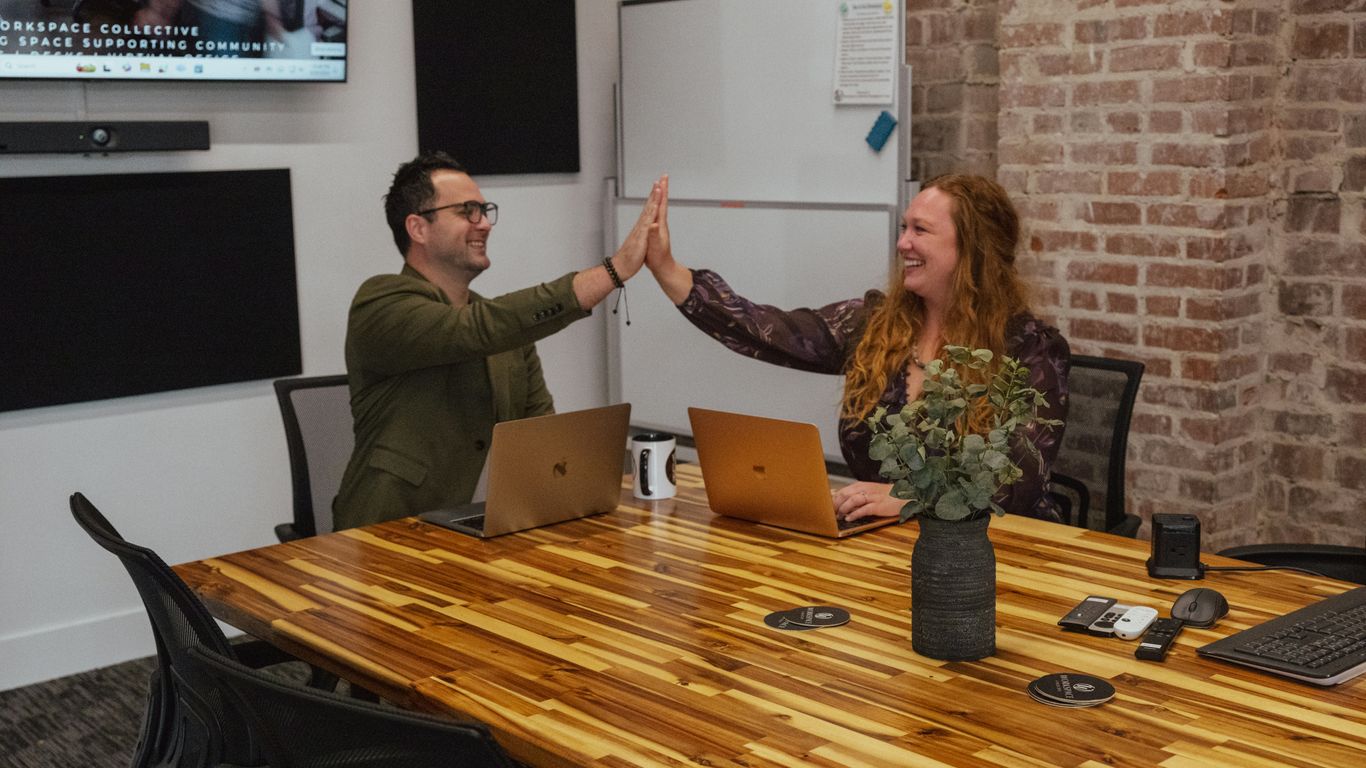 Two people high-fiving in a meeting room.