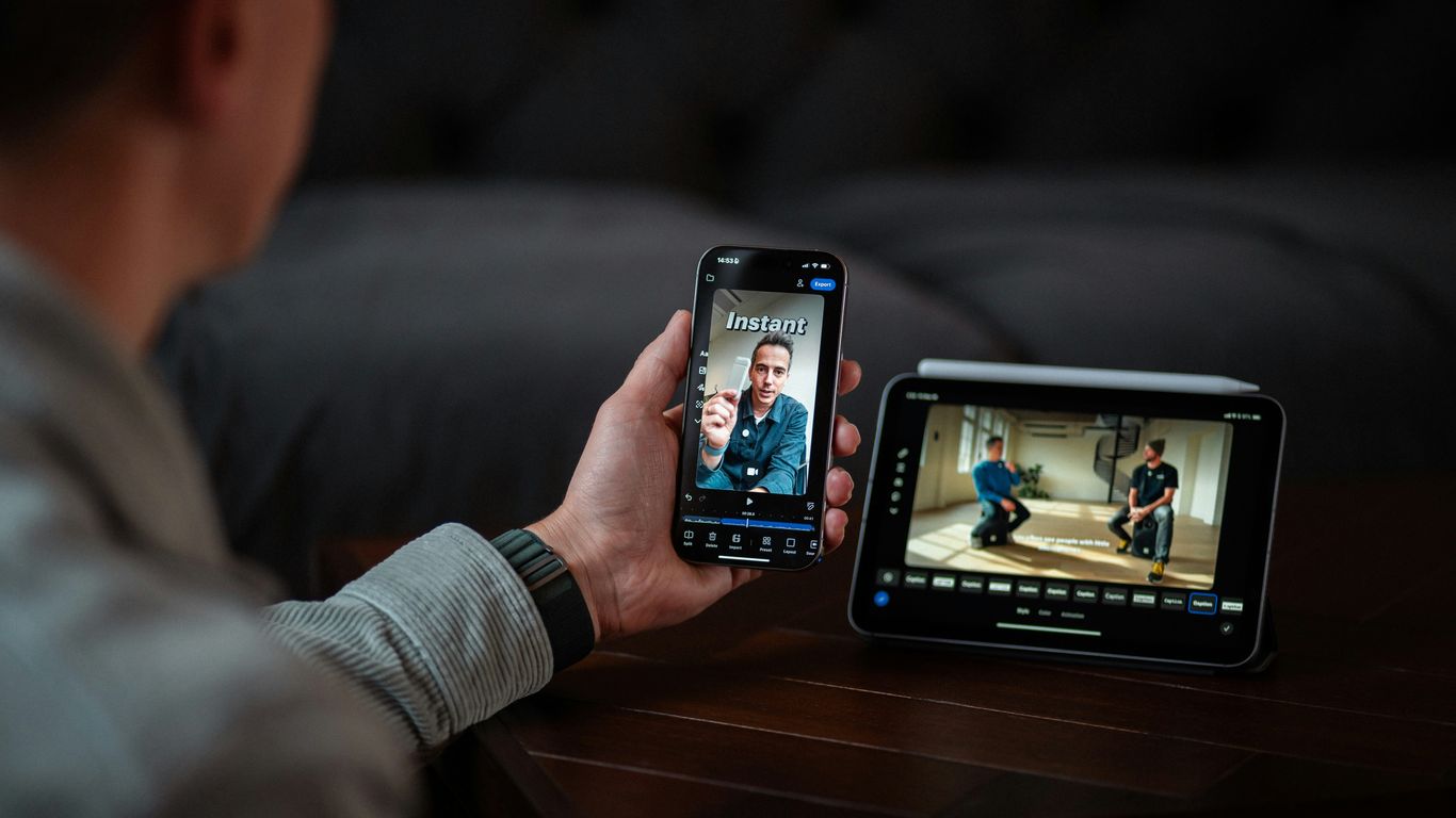 Man video calling on phone next to digital monitor