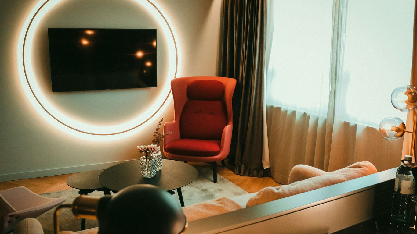 a living room with a red chair and a round mirror