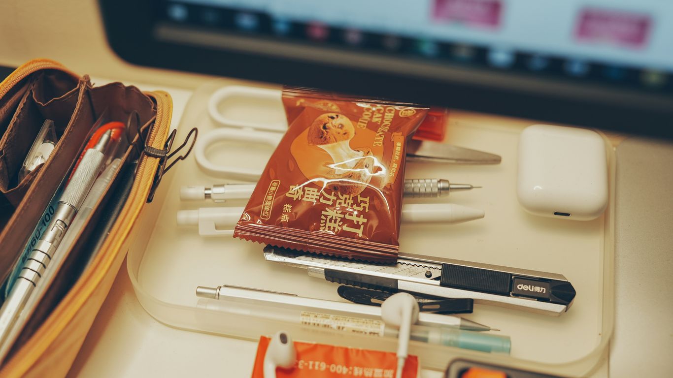 a desk with pens, pens, and a bag on it