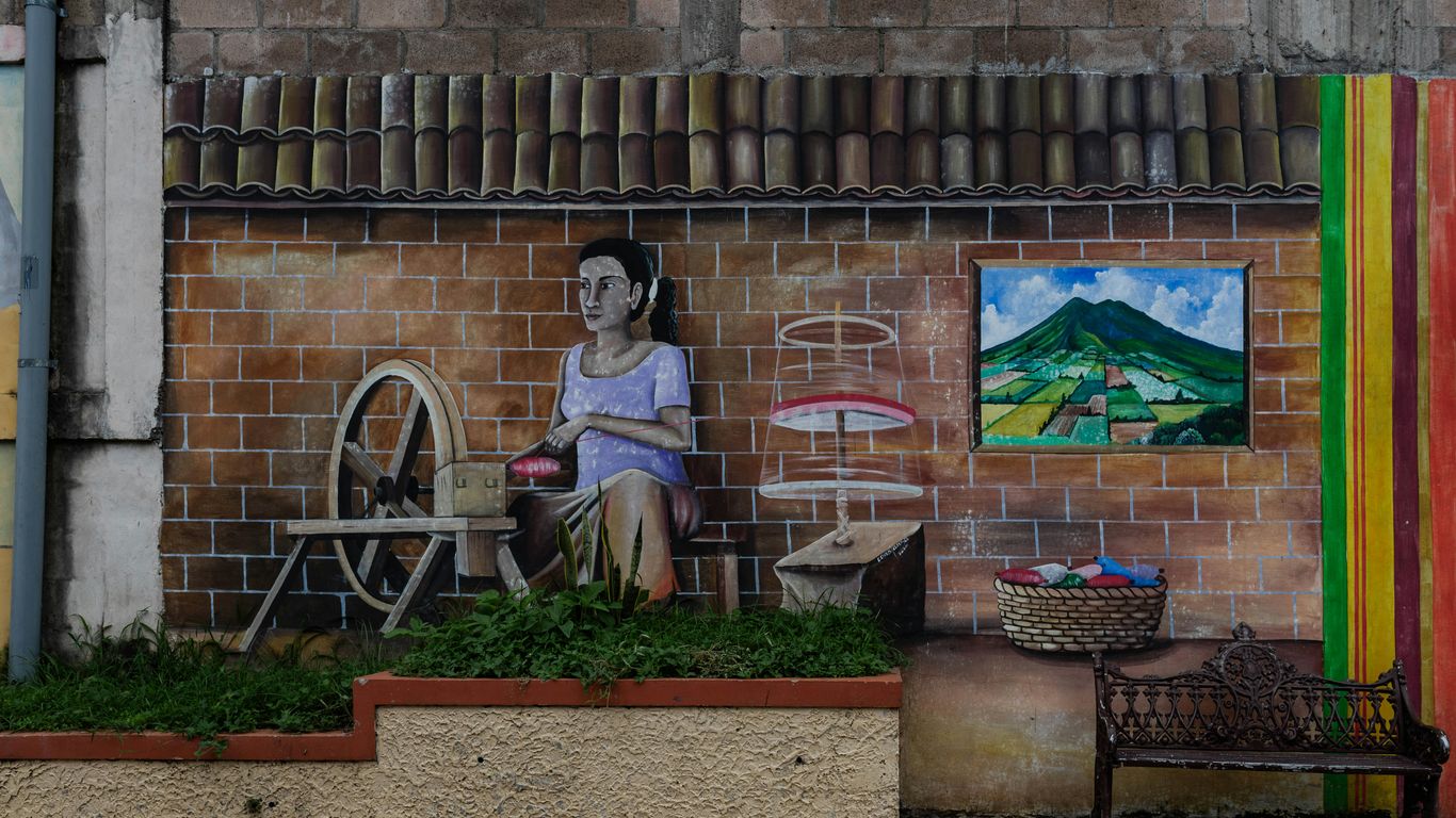 A woman sitting on a bench in front of a building