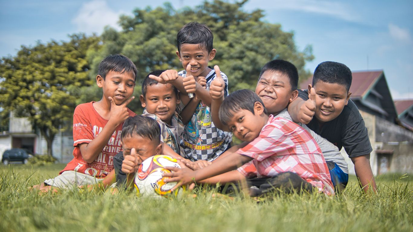 children sitting on green grass field during daytime