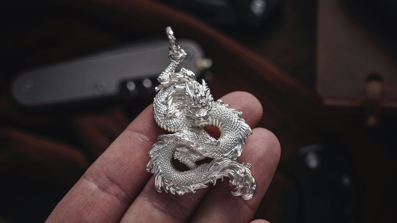 a person holding a silver dragon ring in their hand