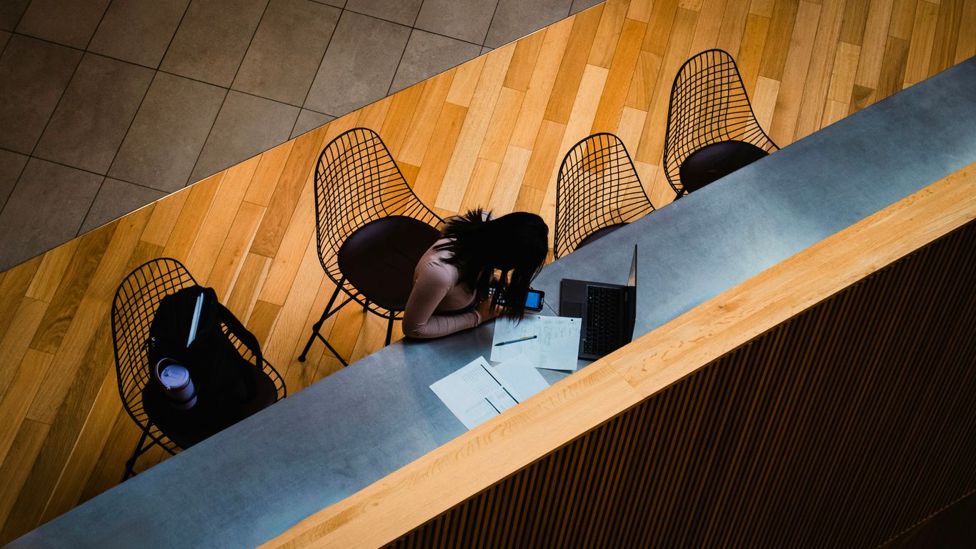Woman resting head on desk at a table.