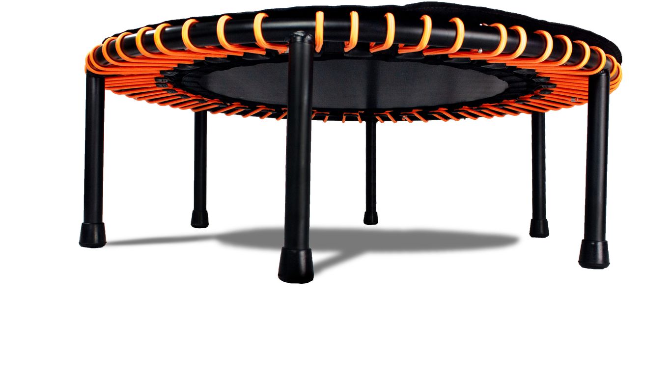 Small round trampoline with orange bands and black legs, isolated.