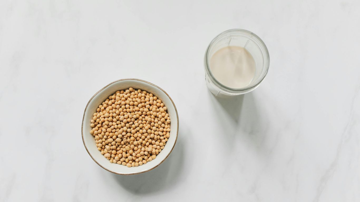 Bowl of soybeans and glass of soy milk on table.