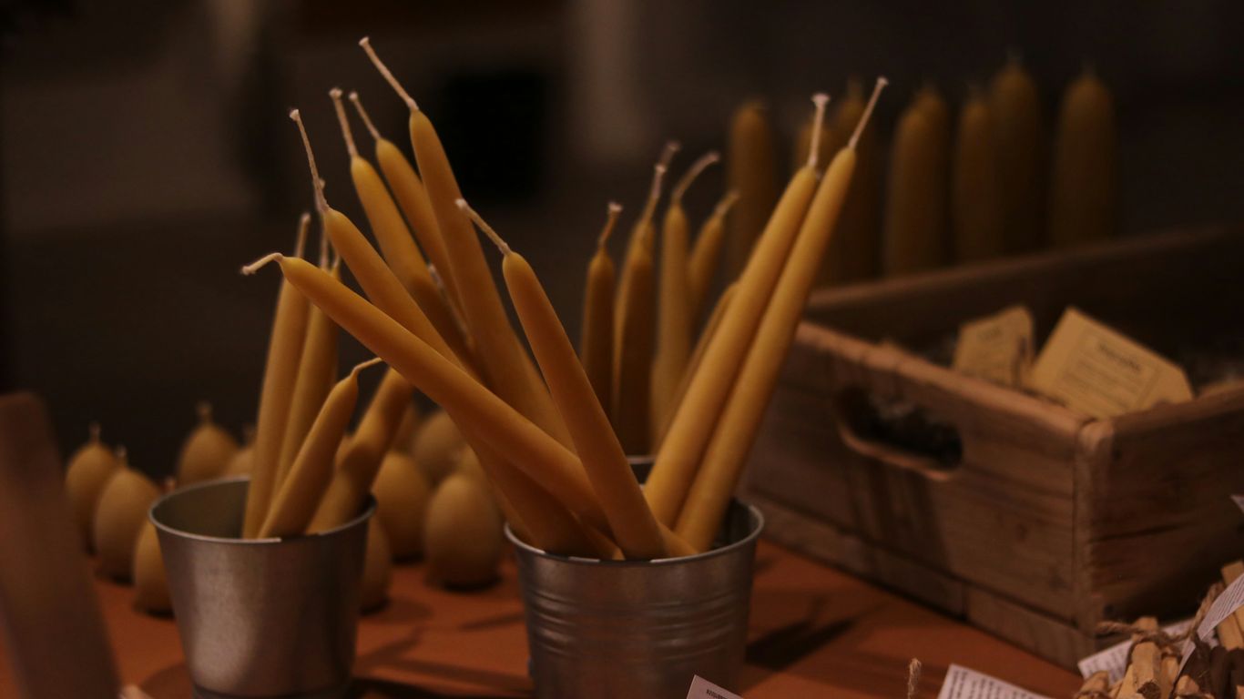 Tall, thin yellow candles in metal containers
