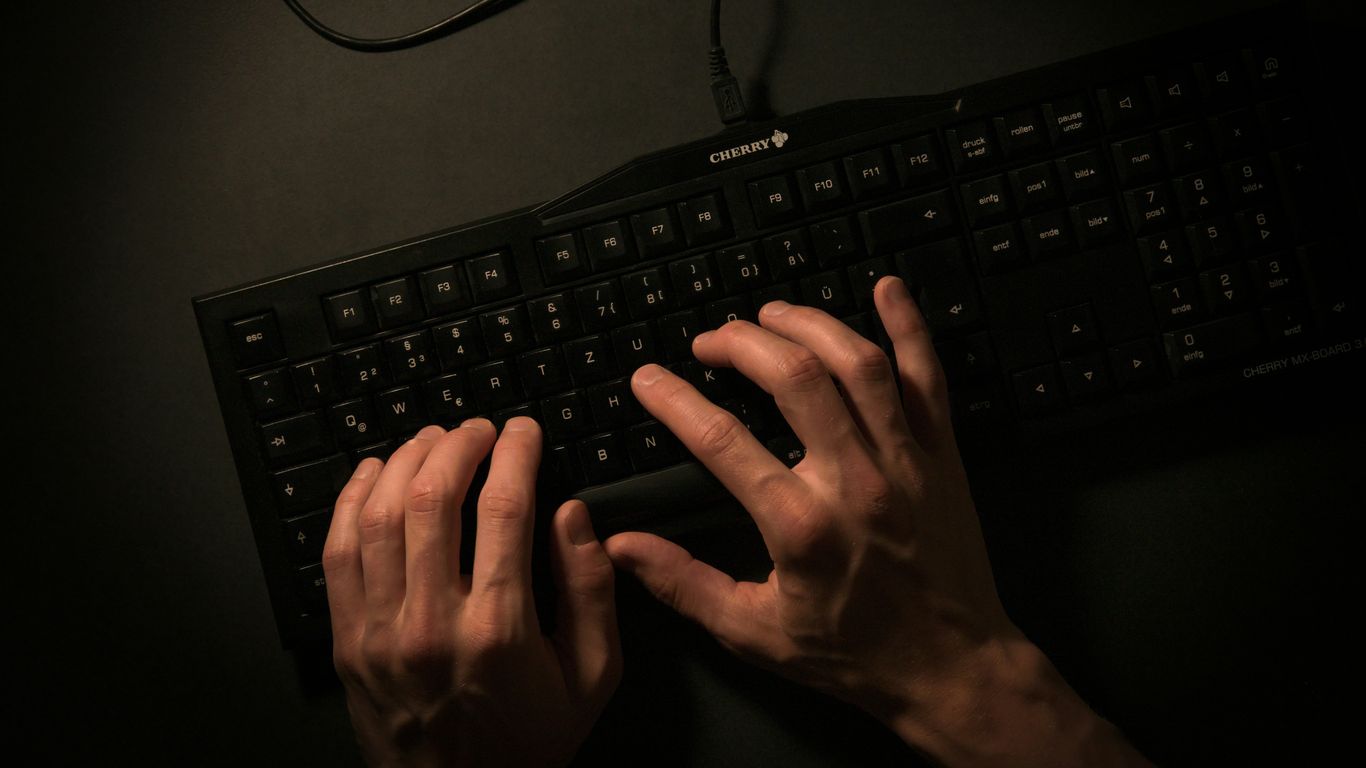 a person is typing on a black keyboard