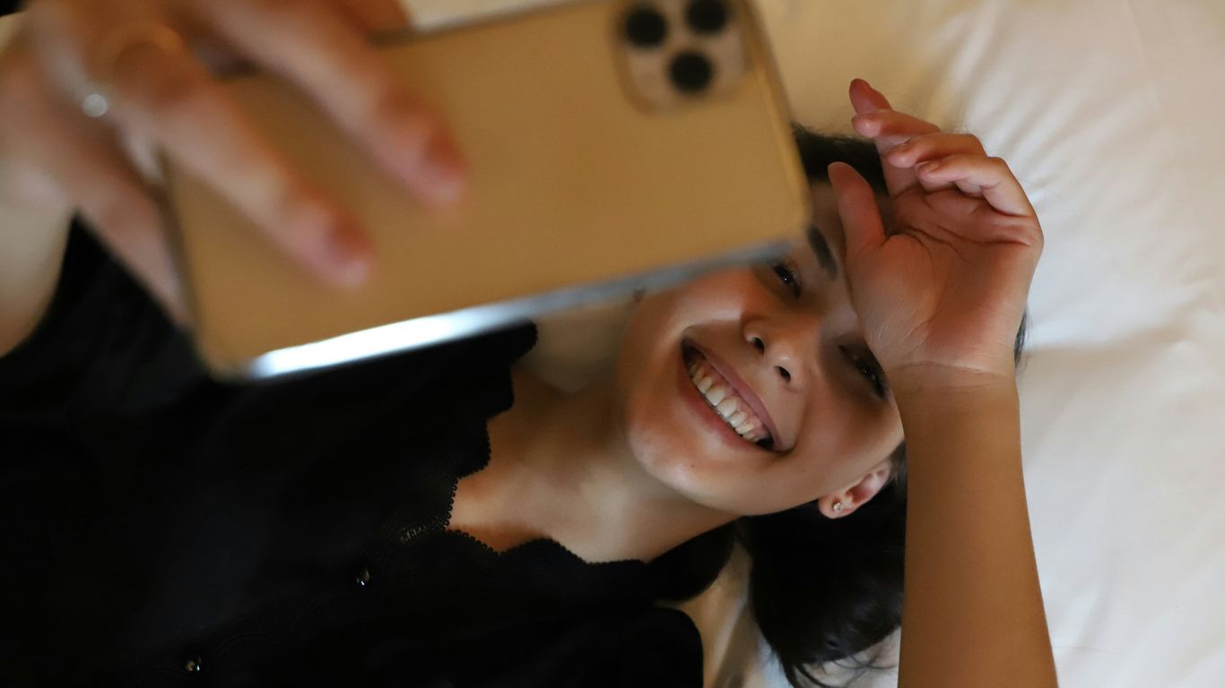 a woman laying on a bed holding a cell phone