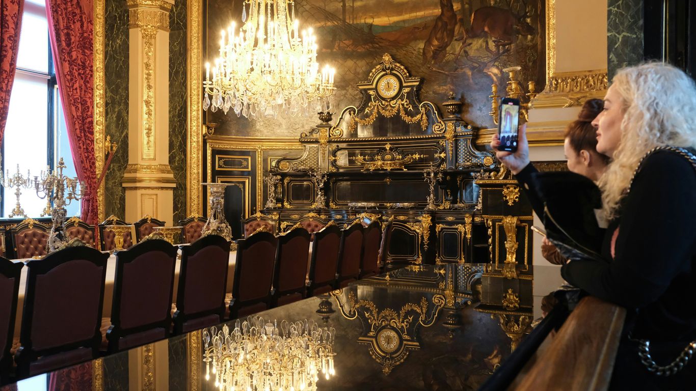 People take photos in a lavish dining room.