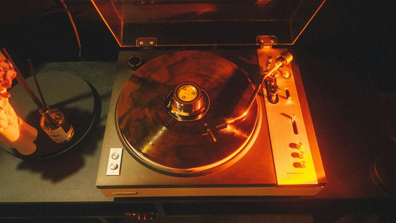 A record player plays vinyl, illuminated by light.