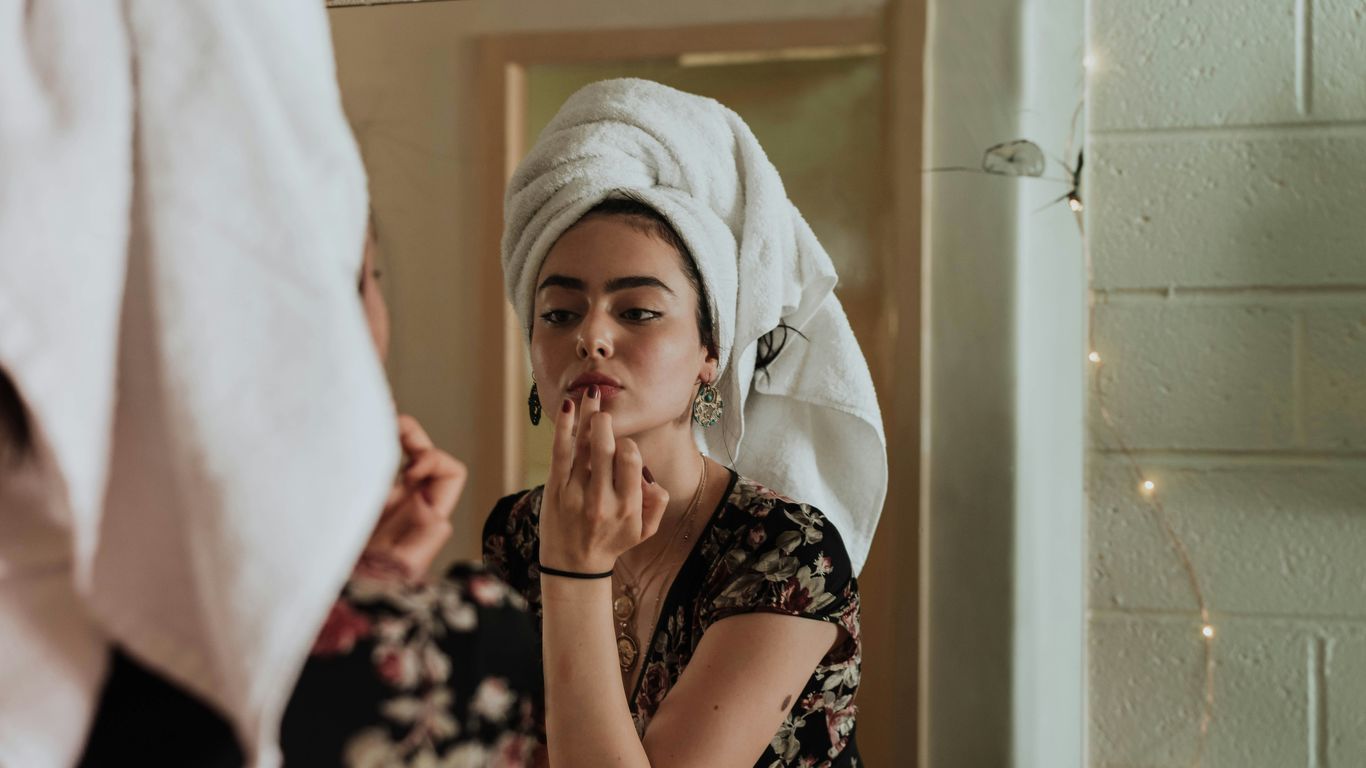 woman putting makeup in front of mirror