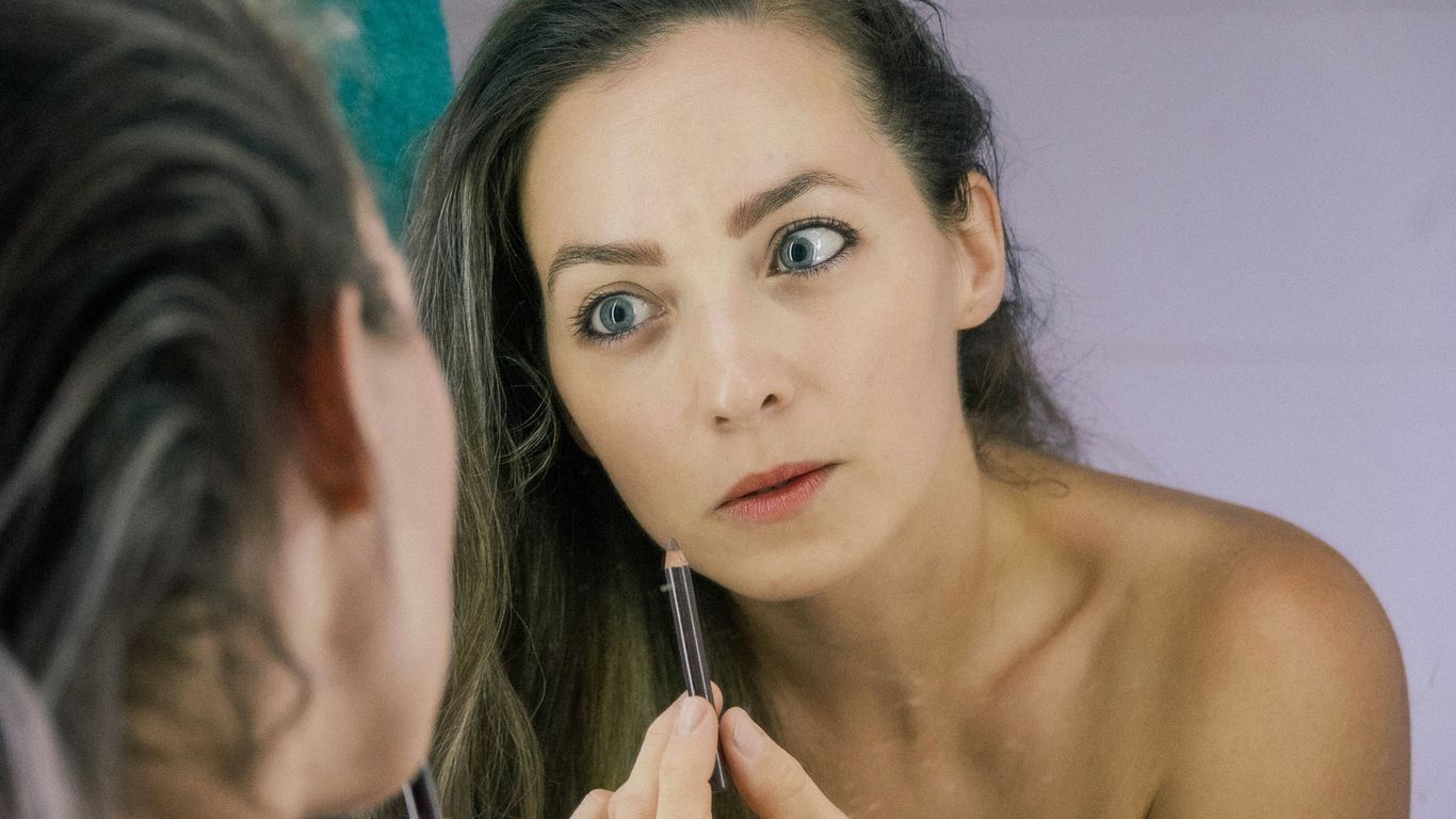 a woman is looking at her reflection in the mirror