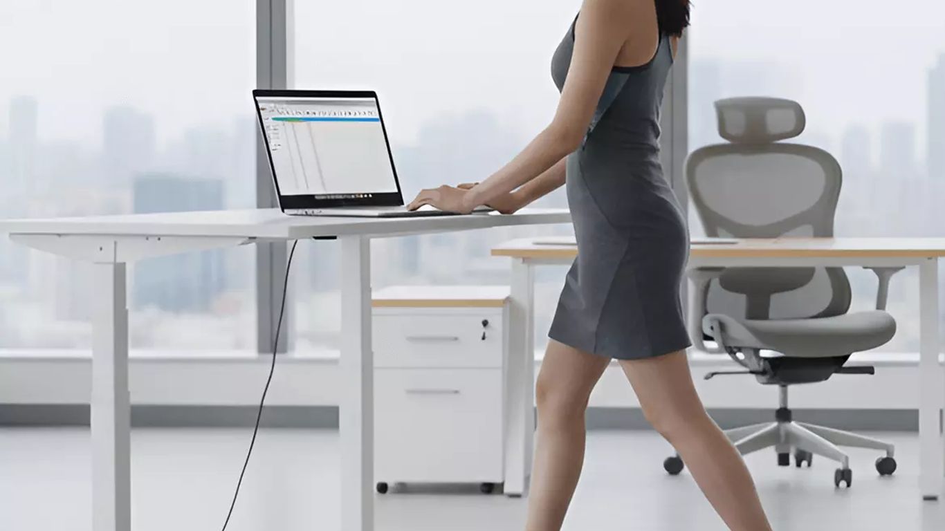 Person walking on treadmill while working on a laptop at a standing desk.