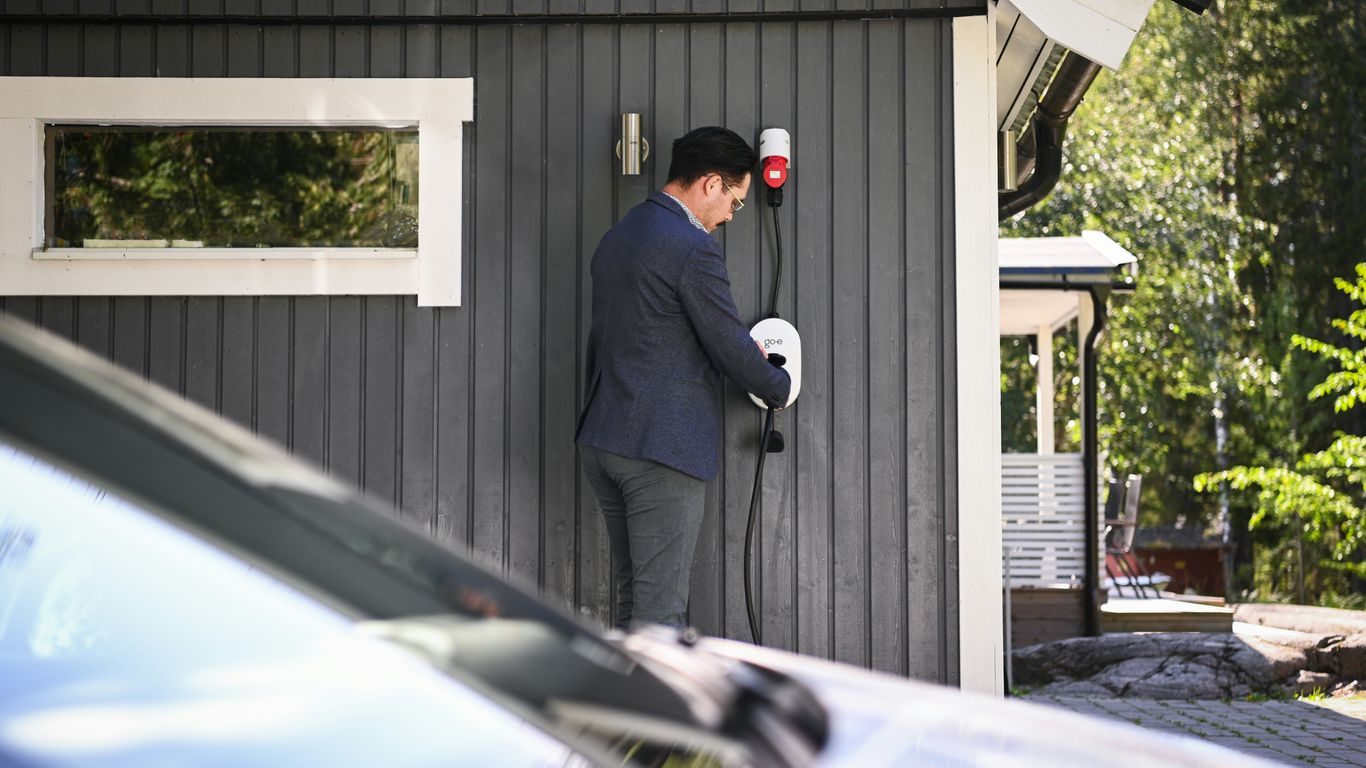 Man plugs in an electric vehicle charging cable.