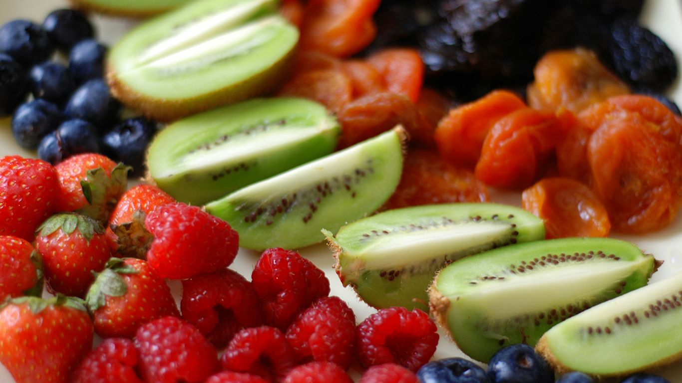 a white plate topped with sliced kiwis and berries