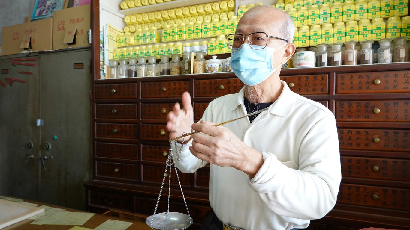 A pharmacist weighs medicine in a traditional shop.