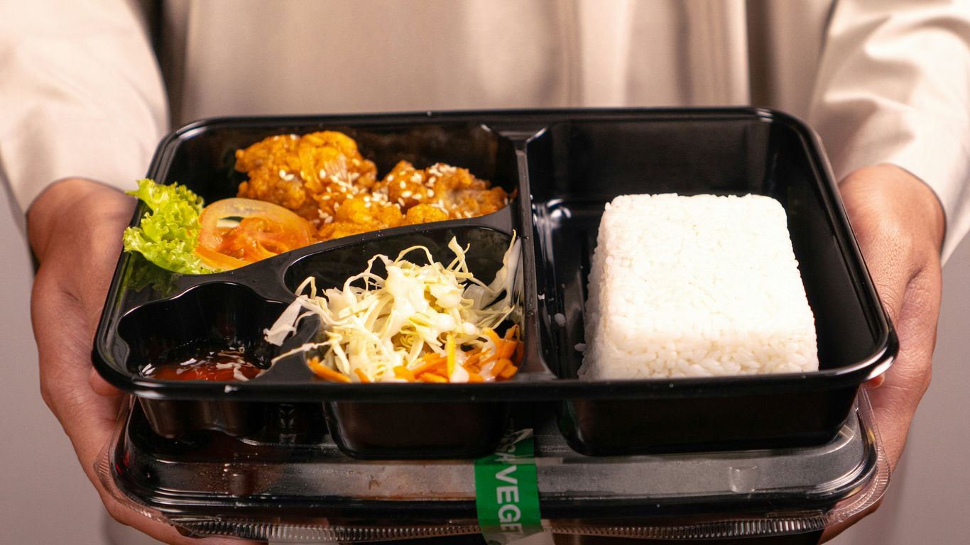 A person holds a bento box meal.