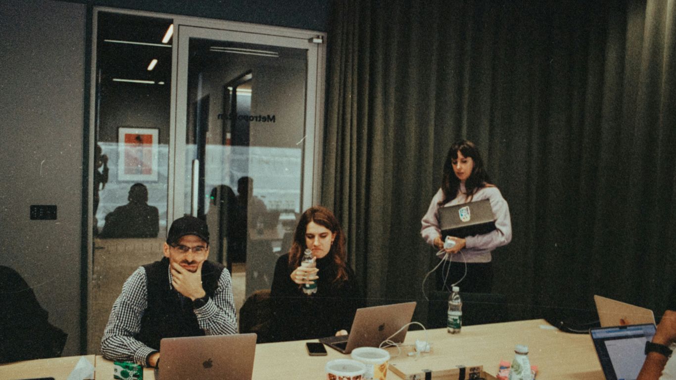 a group of people sitting around a table with laptops