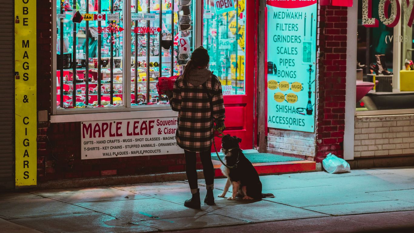 a woman standing on a sidewalk next to a dog