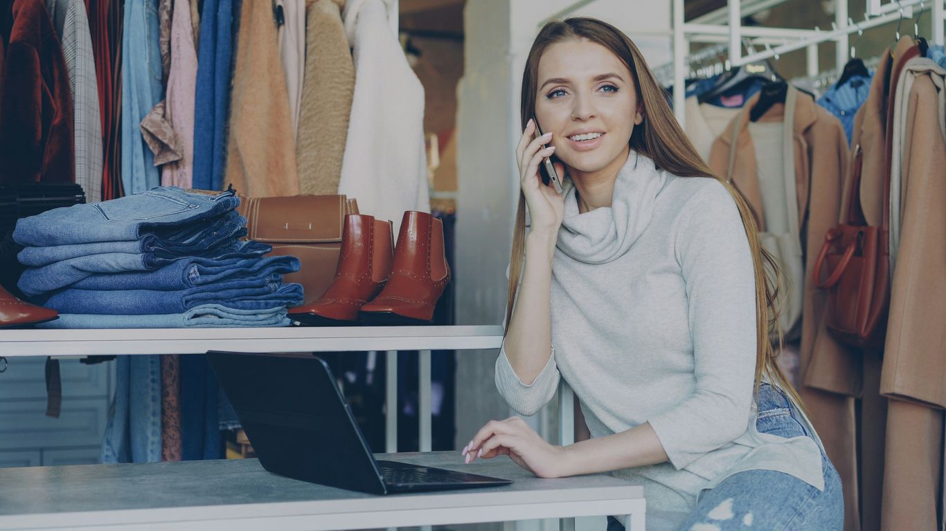 Woman talks on the phone while using a laptop.