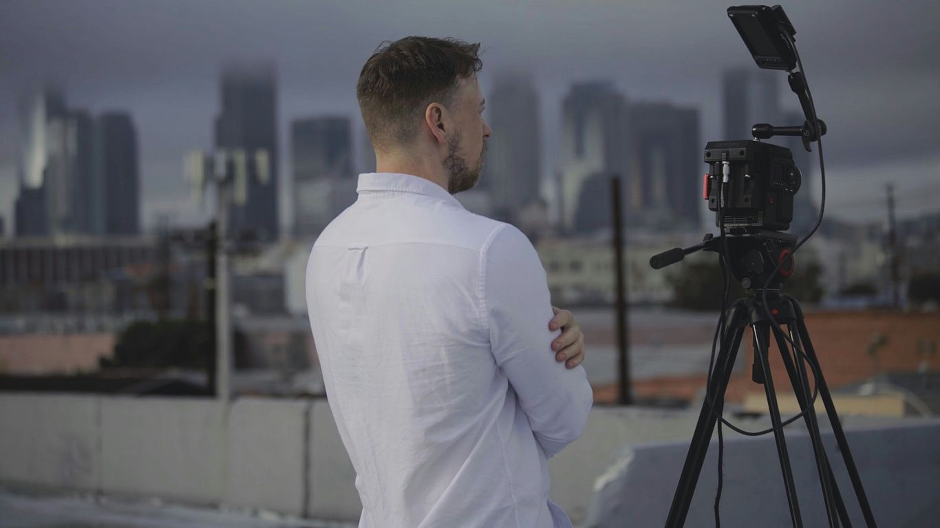 man in white long sleeve shirt standing in front of camera