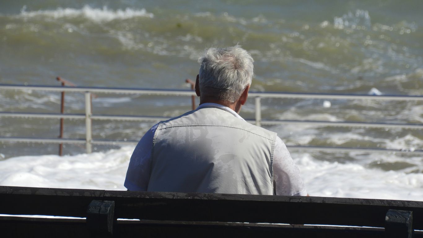a man sitting on a bench looking at the ocean