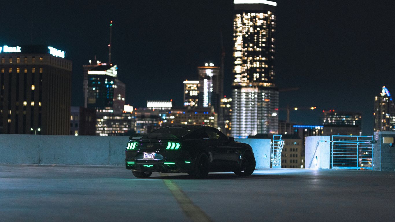 a black sports car driving down a city street at night