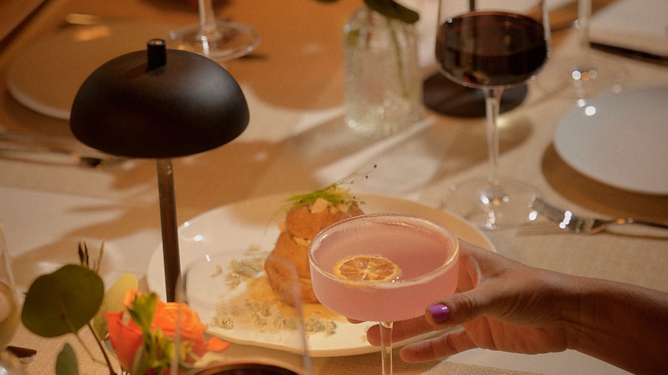A table setting with drinks, food, and flowers, suggesting a dinner party.