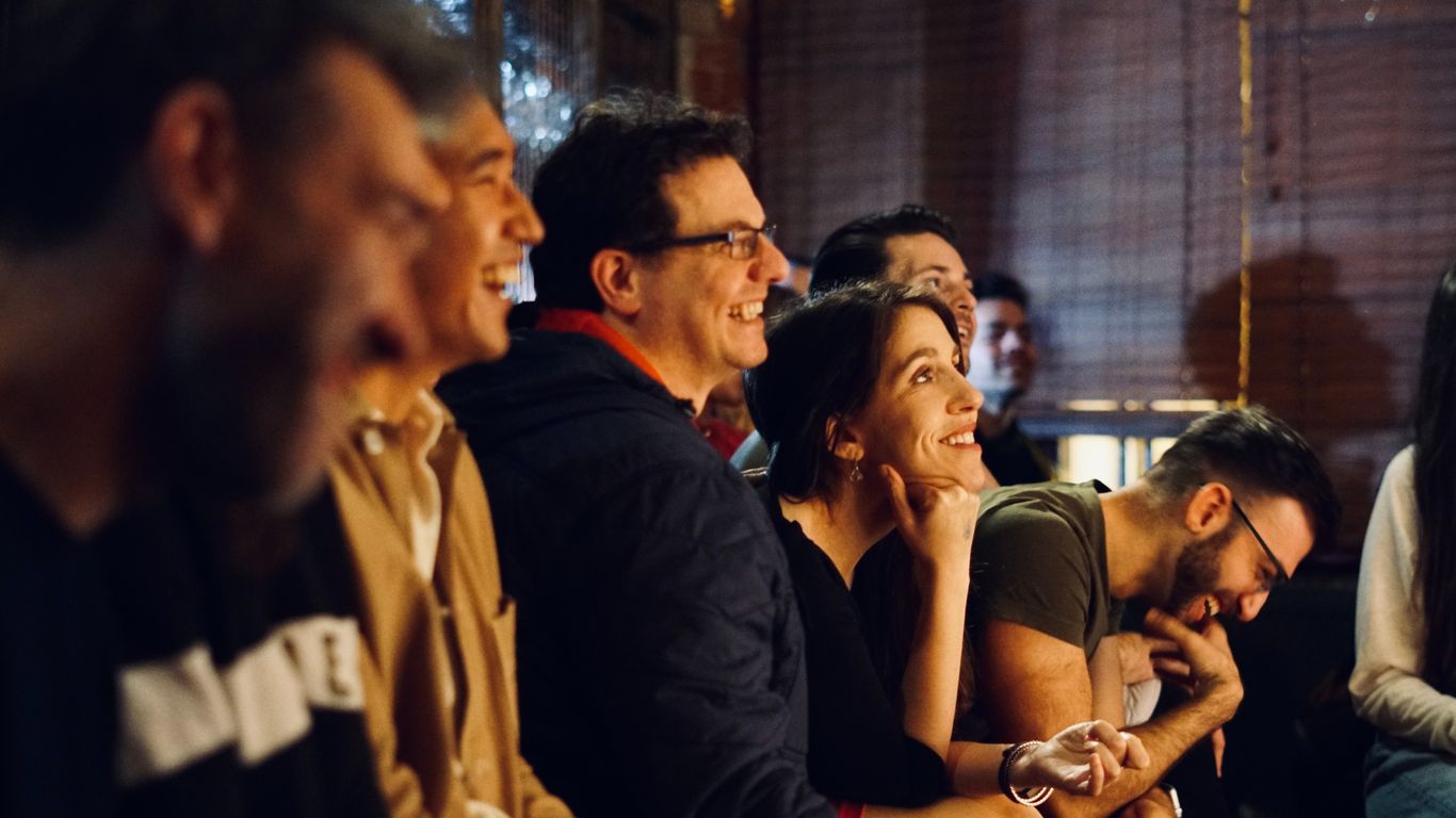 People watching something with smiles and laughter, decorated with banners.