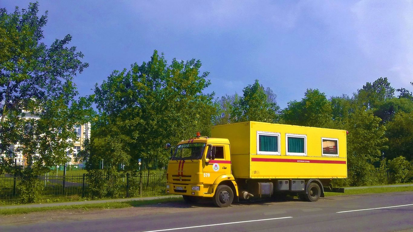 A yellow truck drives down a road.