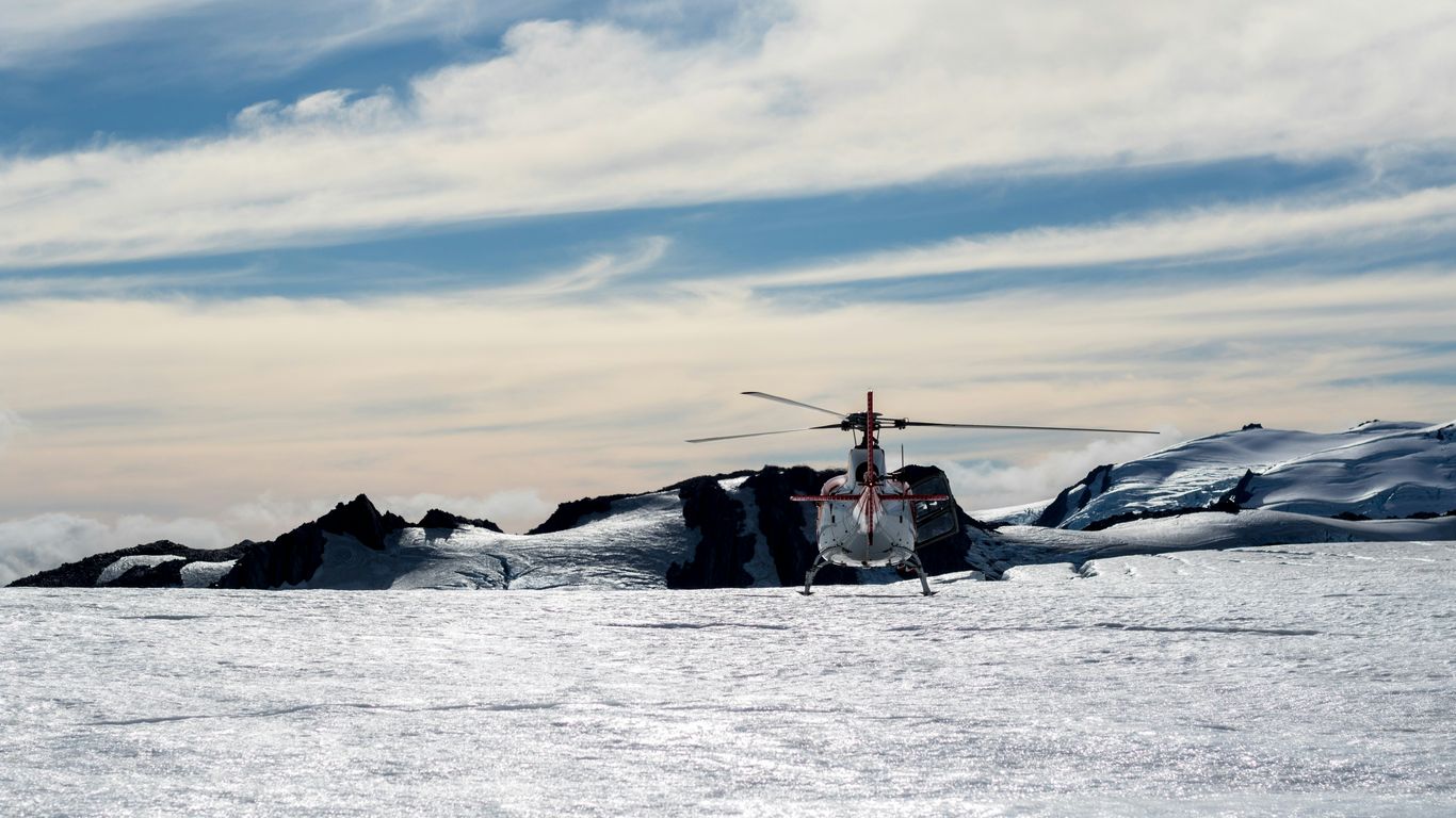 white and red helicopter flying over body of water