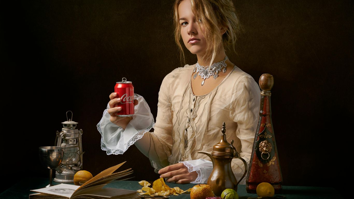 Person in vintage attire holding a Coca-Cola can, surrounded by antiques.