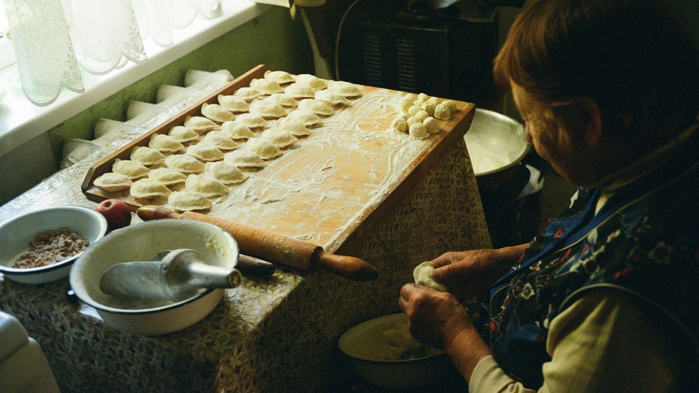 a woman in a kitchen making dough on a table