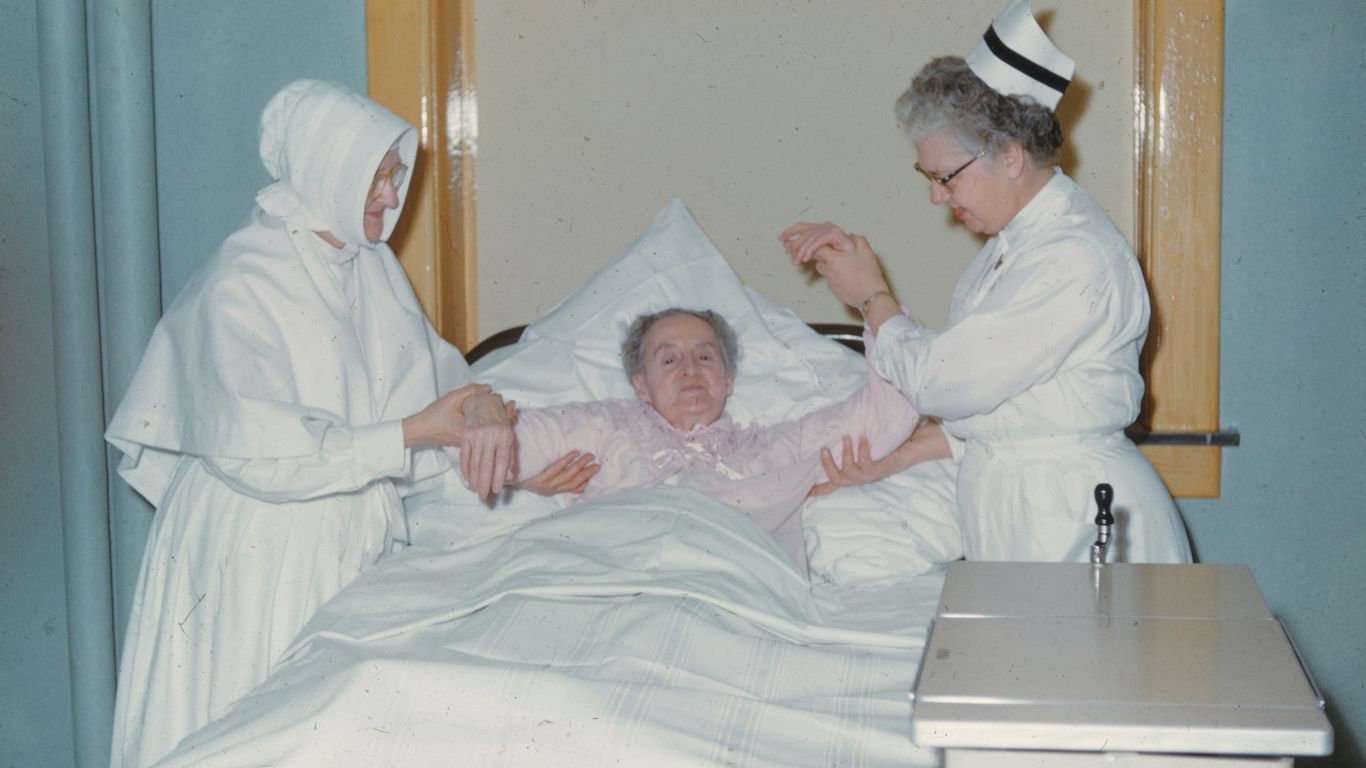 a woman in a hospital bed being assisted by a nurse