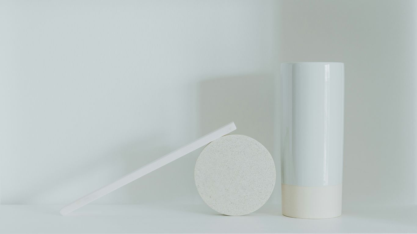 a white vase sitting next to a white round object