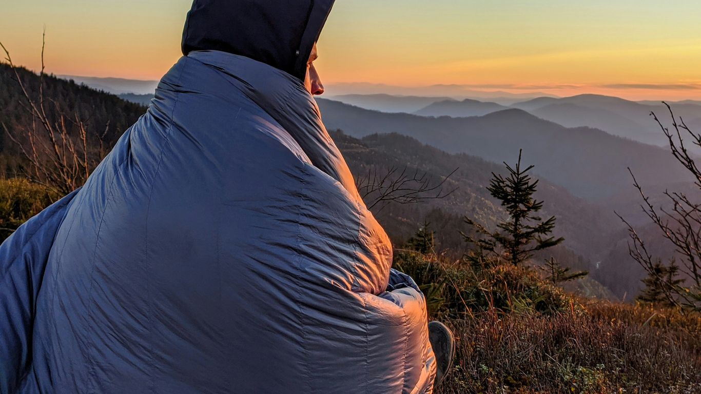 person in white hoodie sitting on blue and white checkered textile
