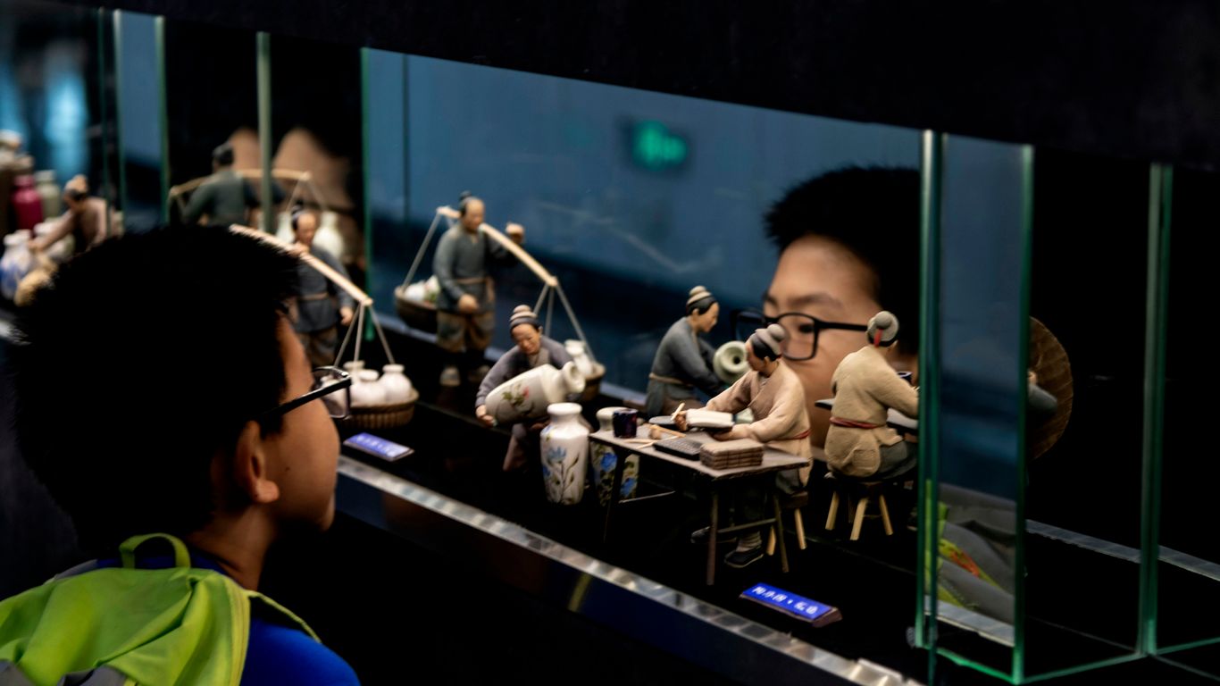 boy looking at human figurines in glass case
