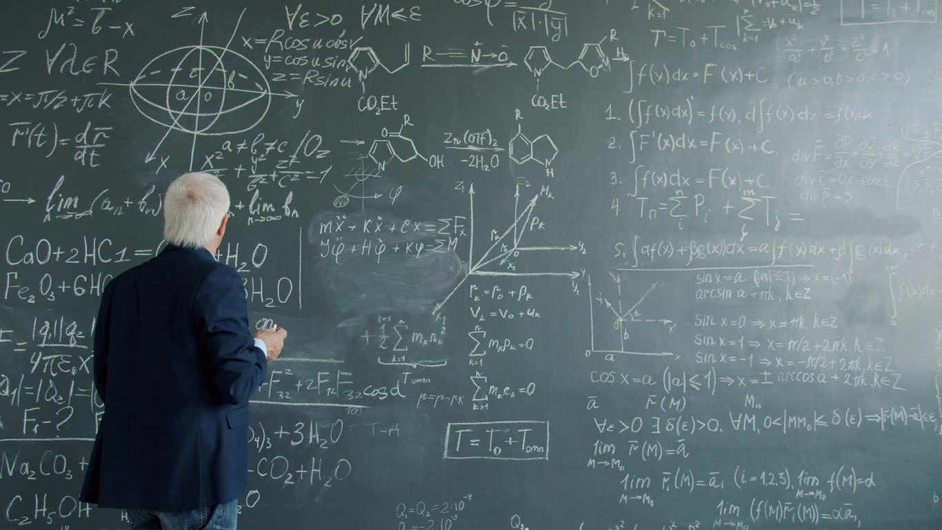 Professor writing complex formulas on a chalkboard