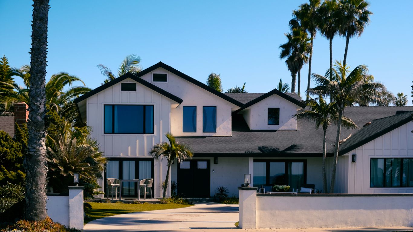 Beautiful white house with palm trees in the background.