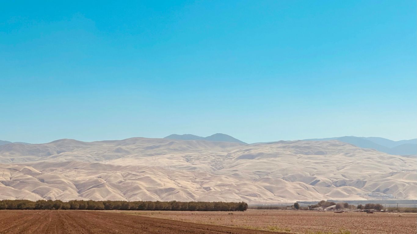 a plowed field with mountains in the background