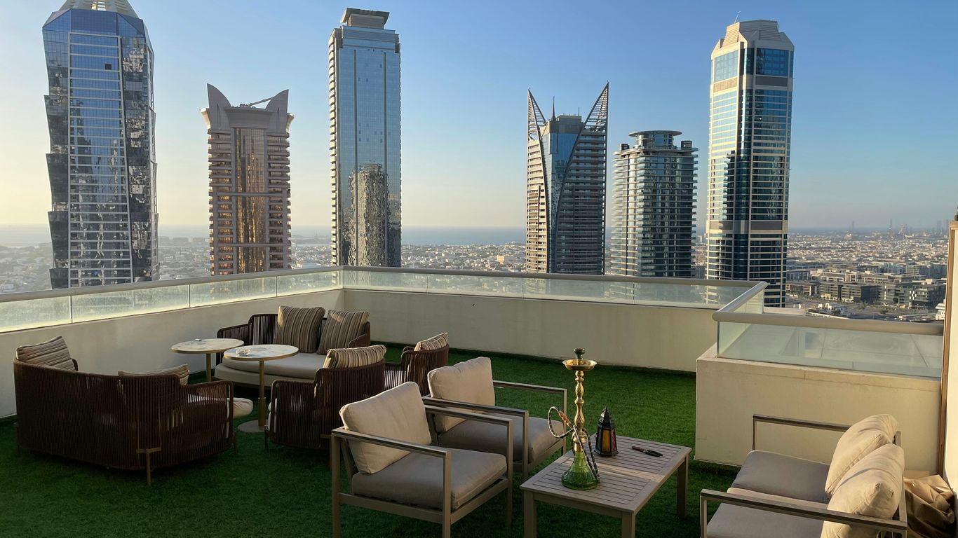 a balcony with chairs, tables, and a view of the city