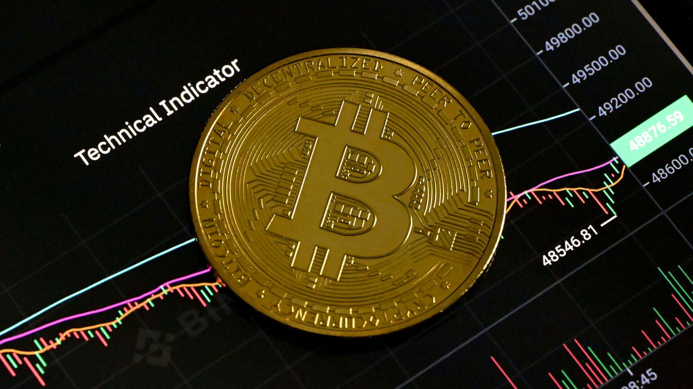 Bitcoin coin on a cryptocurrency trading graph background.