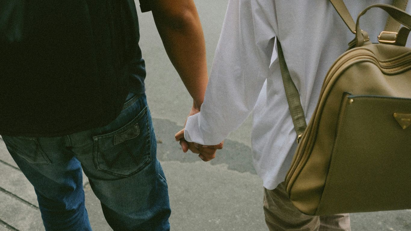 A man and a woman walking down a street holding hands